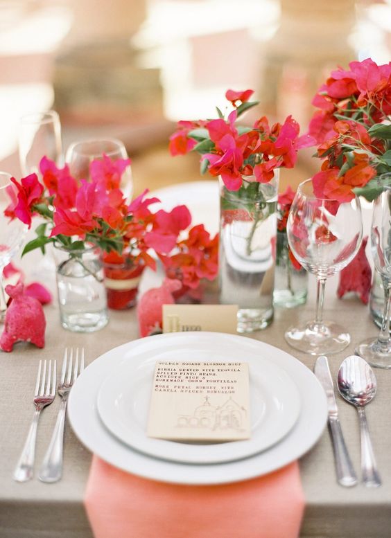 a bold cluster wedding centerpiece of clear glasses and bougainvillea and greenery is a cool idea for a modern wedding