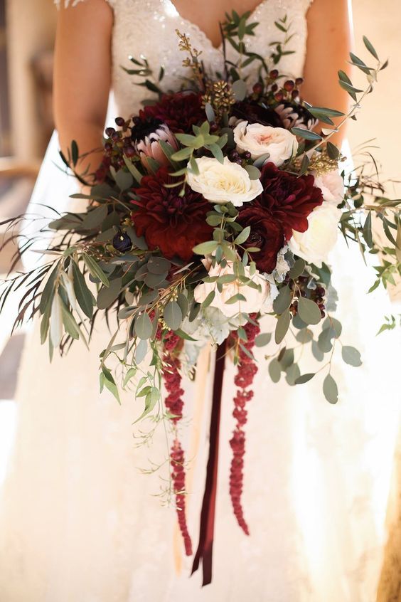 a bold fall wedding bouquet of white and blush roses, burgundy dahlias and king proteas, greenery and amaranthus is cool and chic