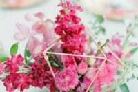 a bold modern wedding centerpiece of a gold himmeli piece, bougainvillea, pink blooms and greenery is ultimate for summer