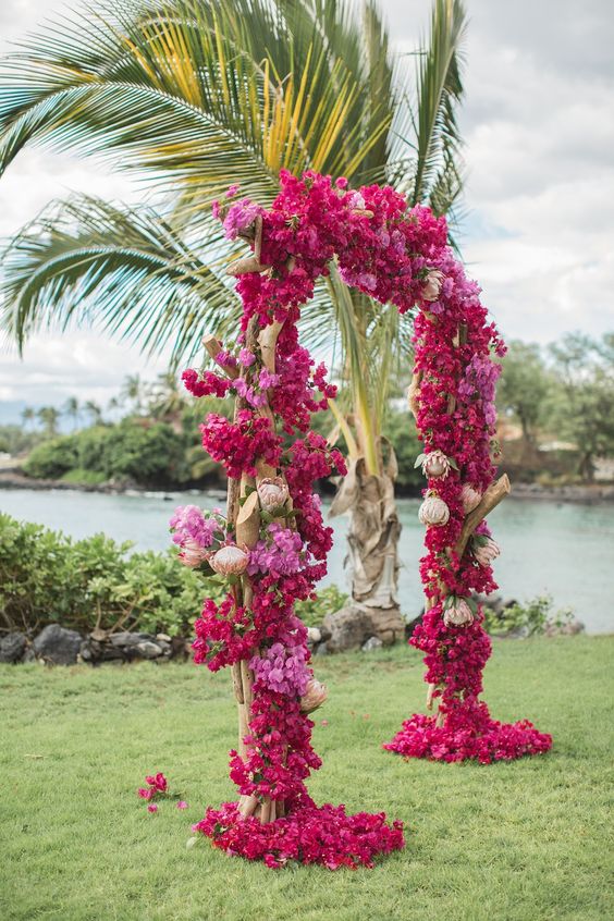 a bold tropical wedding arch covered with bougainvillea and king proteas is a creative and unique idea for a tropical celebration