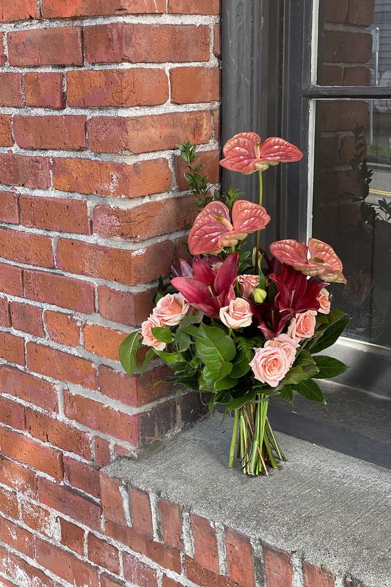 a bold wedding bouquet of blush roses, burgundy lilies and pink anthurium plus some leaves is a cool idea