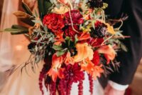 a bold wedding bouquet of red roses, lilies and callas, some deep purple blooms, twigs, leaves and amaranthus is amazing for the fall