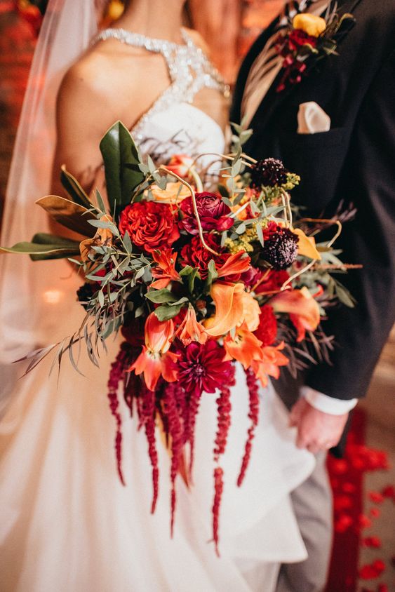 a bold wedding bouquet of red roses, lilies and callas, some deep purple blooms, twigs, leaves and amaranthus is amazing for the fall