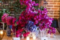 a bold wedding centerpiece of bougainvillea, blue hydrangeas and pink dahlias for a Mediterranean wedding