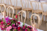 a bold wedding centerpiece of bougainvillea, pink roses and greenery and candles in tall glasses is a lovely idea for a wedding