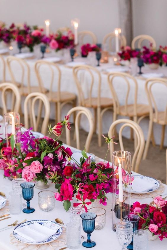 a bold wedding centerpiece of bougainvillea, pink roses and greenery and candles in tall glasses is a lovely idea for a wedding