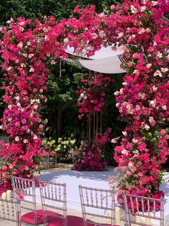 a breathtaking wedding chuppah covered with bougainvillea and blush blooms plus greeneyr and white fabric is a cool idea for a summer wedding