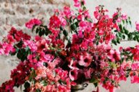 a bright and lush textural wedding centerpiece of bougainvillea, pink and red blooms and greenery is a jaw-dropping idea for a destination wedding