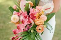 a bright tropical wedding bouquet of pink orchids, yellow ranunculus, neutral anthurium, greenery and fronds