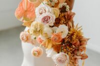 a bright wedding bouquet of blush and peachy blooms, roses and ranunculus, anthurium and dahlias plus fronds