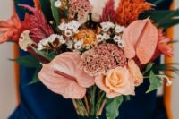 a bright wedding bouquet of blush anthurium, orange, pink and red blooms, some fillers and greenery