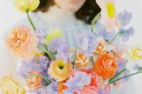 a bright wedding bouquet of yellow and orange ranunculus, lilac sweet peas is a cool way to juxtapose colors