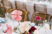 a bright wedding centerpiece of burgundy roses, white ranunculus, peonies and carnations, pink anthurims is wow