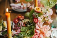 a bright wedding centerpiece of pink blooms, dried flowers, green anthurims and colorful candles is wow