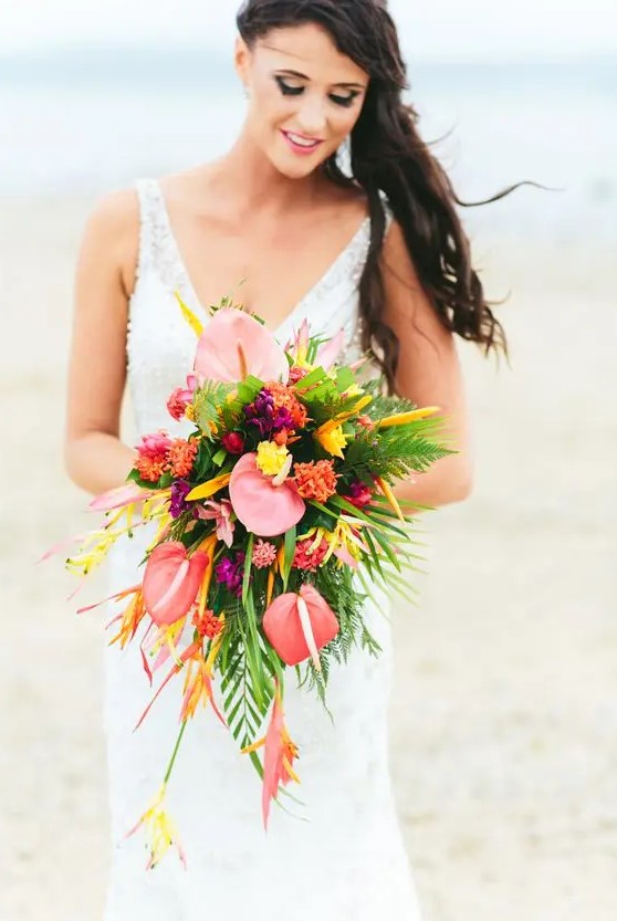 a cascading bouquet with much greenery, salmon pink, orange and yellow blooms