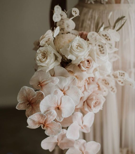 a cascading wedding bouquet of white roses, blush orchids, lunaria and grasses is a luxurious idea for a modern wedding with a twist