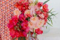 a catchy and colorful wedding bouquet of bougainvillea, blush and peachy roses, greenery and amaranthus for a bold summer wedding
