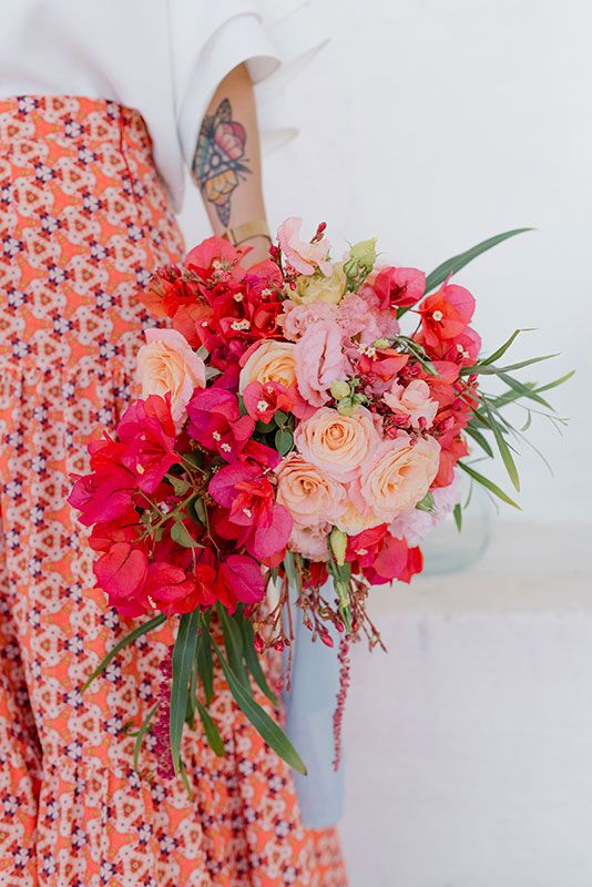 a catchy and colorful wedding bouquet of bougainvillea, blush and peachy roses, greenery and amaranthus for a bold summer wedding