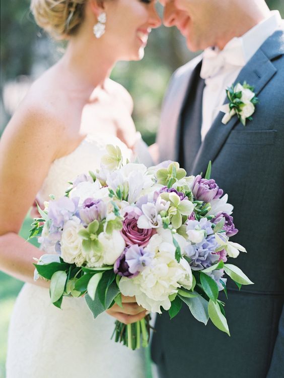 a catchy wedding bouquet of white peonies, fuchsia blooms, irises, white and blue sweet peas and greenery for spring