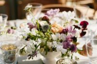 a catchy wedding centerpiece of allium, white and purple sweet peas, greenery and some other blooms mixed for a relaxed look