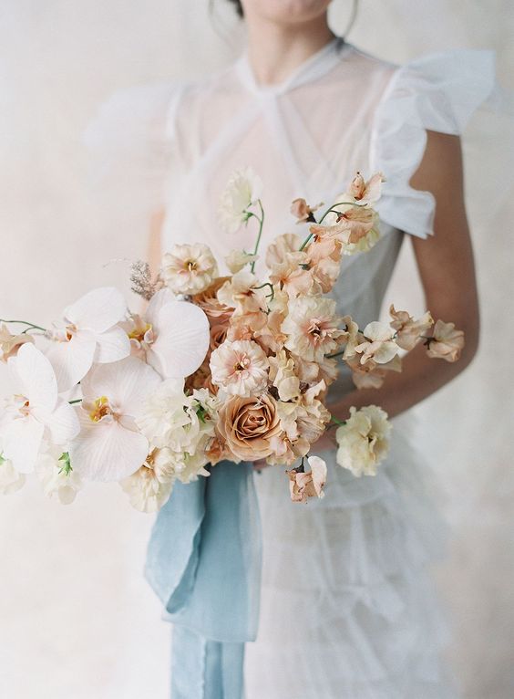 a chic and beautiful wedding bouquet of sweet peas, some other blooms and blush orchids is an exquisite statement