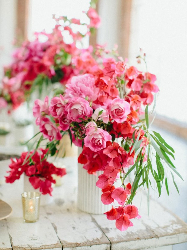 a chic and bold wedding centerpiece of pink roses and bougainvillea plus some greenery is amazing for destination wedding