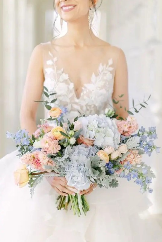 a chic pastel wedding bouquet of blue hydrangeas, blush carnations, yellow roses and ranunculus, greenery is a stylish idea for spring