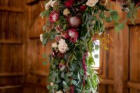a chic rustic wedding arch with greenery, blush, mauve and burgundy roses, king proteas and amaranthus for a touch of color and texture