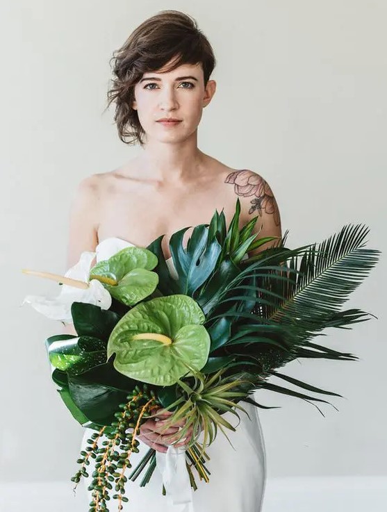 a chic textural and dimensional bouquet with large tropical leaves, cascading greenery and orchids