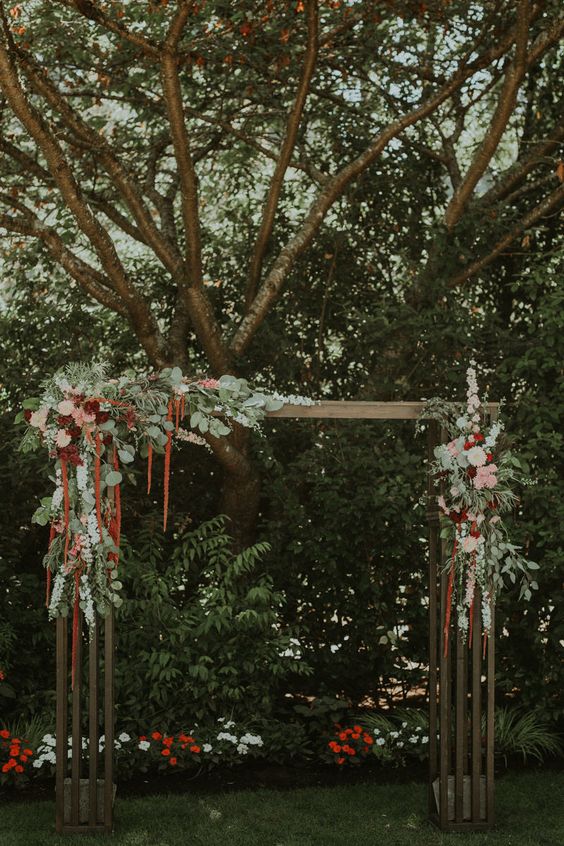 a chic wedding arch with greenery, blush and burgundy roses and dahlias and amaranthus for an elegant fall wedding