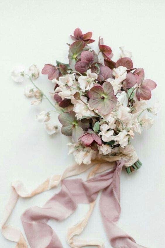 a chic wedding bouquet of blush sweet peas and dark blooms for a contrast, mauve and neutral ribbons is refined