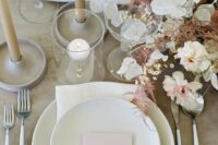 a chic wedding tablescape with a lunaria, carnation and astilbe wedding centerpiece, neutral porcelain and candles