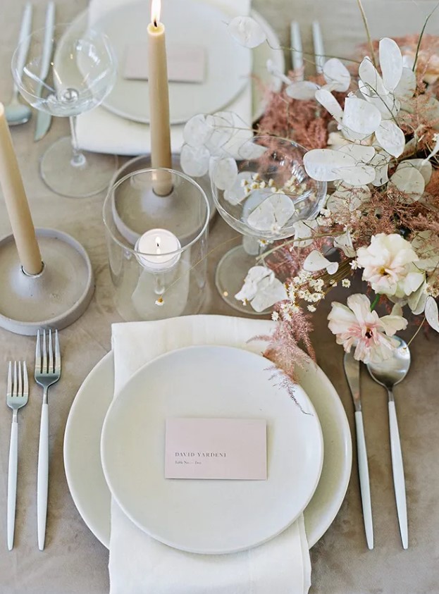 a chic wedding tablescape with a lunaria, carnation and astilbe wedding centerpiece, neutral porcelain and candles