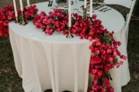 a classic wedding table runner of bougainvillea and greenery dotted with candles is an amazing statement for a wedding table