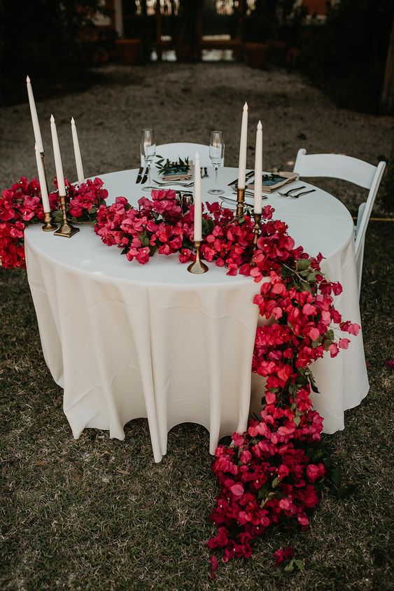 a classic wedding table runner of bougainvillea and greenery dotted with candles is an amazing statement for a wedding table