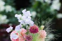 a cluster wedding centerpiece of lilac sweet peas, pink dahlias and fuchsia mums and greenery is a cool idea for a summer wedding
