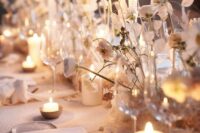 a cluster wedding centerpiece of some blooms, seed pods and lunaria plus white pillar candles is amazing