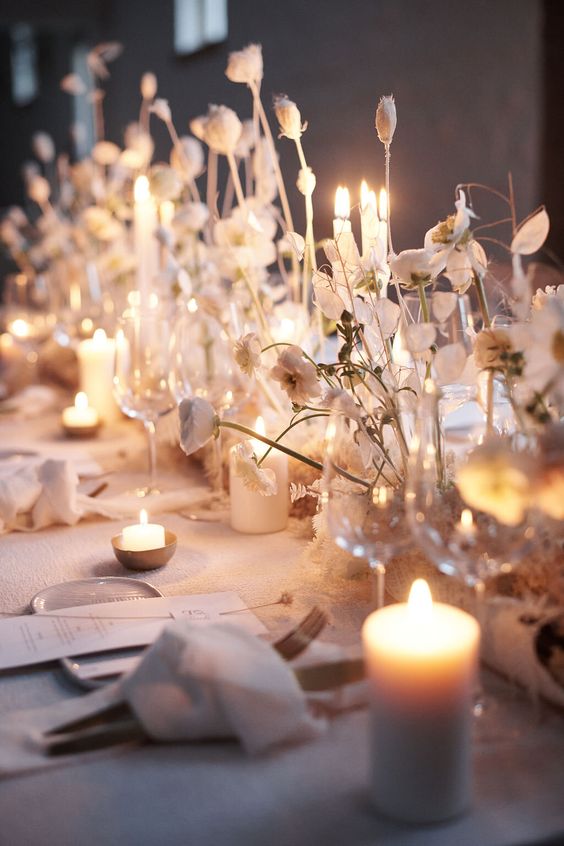 a cluster wedding centerpiece of some blooms, seed pods and lunaria plus white pillar candles is amazing