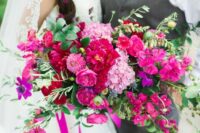 a colorful and dimensional wedding bouquet of bougainvillea, pink ranunculus and mums, purple anemones and greenery