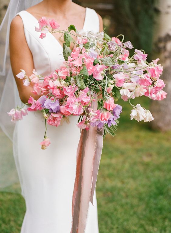 a colorful and dimensional wedding bouquet of pink, blush and purple sweet peas plus leaves is amazing for spring or summer