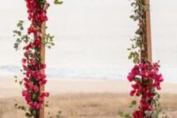 a colorful wedding arch covered with eucalyptus and bougainvillea is a bold and cool idea for a summer boho wedding