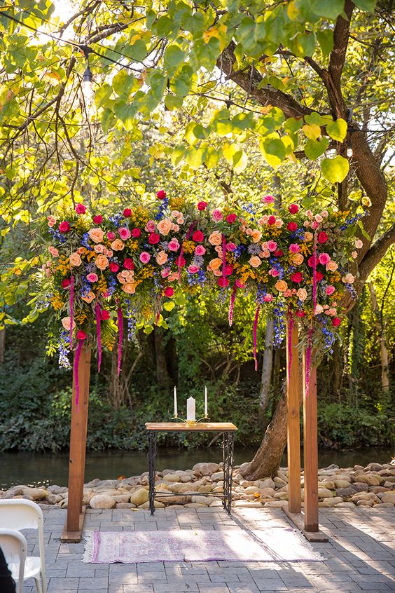 a colorful wedding arch of blush, light pink, yellow, peachy blooms, greenery, amaranthus is gorgeous for a bright wedding