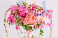 a colorful wedding bouquet of a coral peony, bougainvillea, blue blooms and lavender, greenery is a summer wedding solution