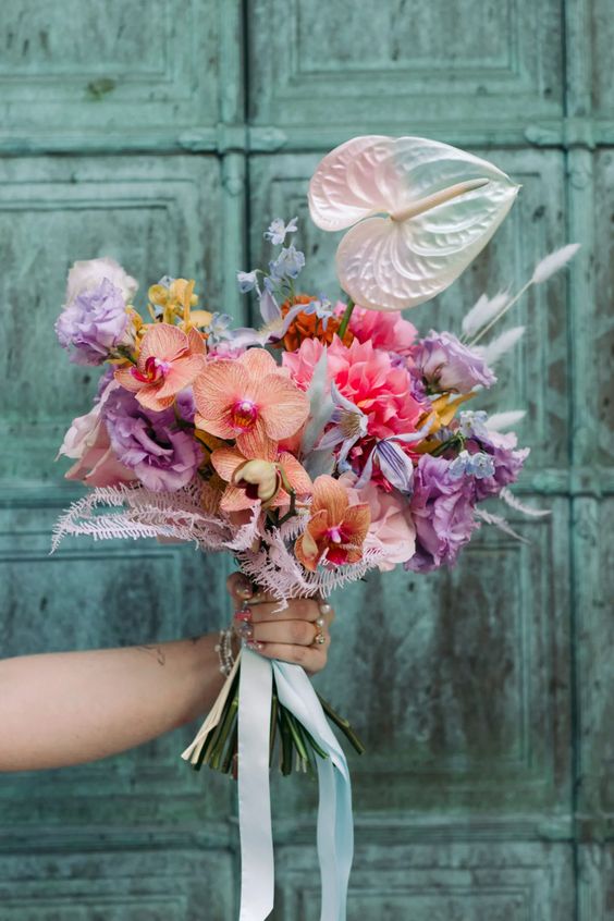 a colorful wedding bouquet of bold purple and pink blooms, peachy orchids and a neutral anthurium plus bunny tails is a lovely idea