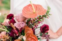 a colorful wedding bouquet of coral anthurium, pink and fuchsia blooms and greenery is a bold and catchy idea