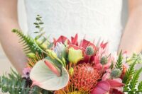 a colorful wedding bouquet of pink roses and orchids, neutral ones, thistles, greenery and some tropical blooms including anthurium