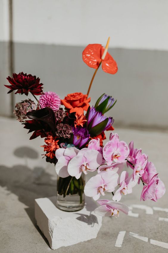 a colorful wedding centerpiece of anthurium, orchids, roses and dahlias is a catchy and bright solution for a bold wedding