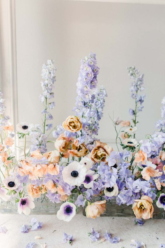 a colorful wedding centerpiece of lilac anemones, rust tulips, periwinkle and lilac sweet peas for a spring or summer wedding
