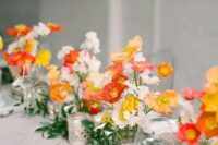 a colorful wedding centerpiece of red, yellow and white poppies and greenery plus candles is a beautiful idea for summer