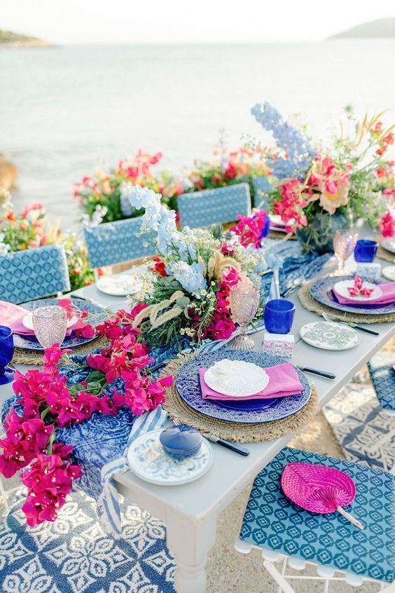 a colorful wedding table runner with bougainvillea, blue and pink blooms and greenery is stunning for a Mediterranean wedding
